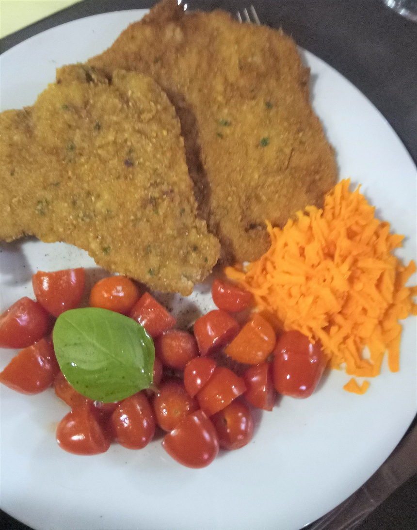 Schnitzel in Kräuterpanade mit Mohrrübe und Tomate als Secondo